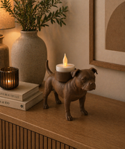 Matte bruine Staffordshire Bull Terrier waxinelichthouder met LED-waxinelichtje op houten kast in warme huiselijke omgeving.